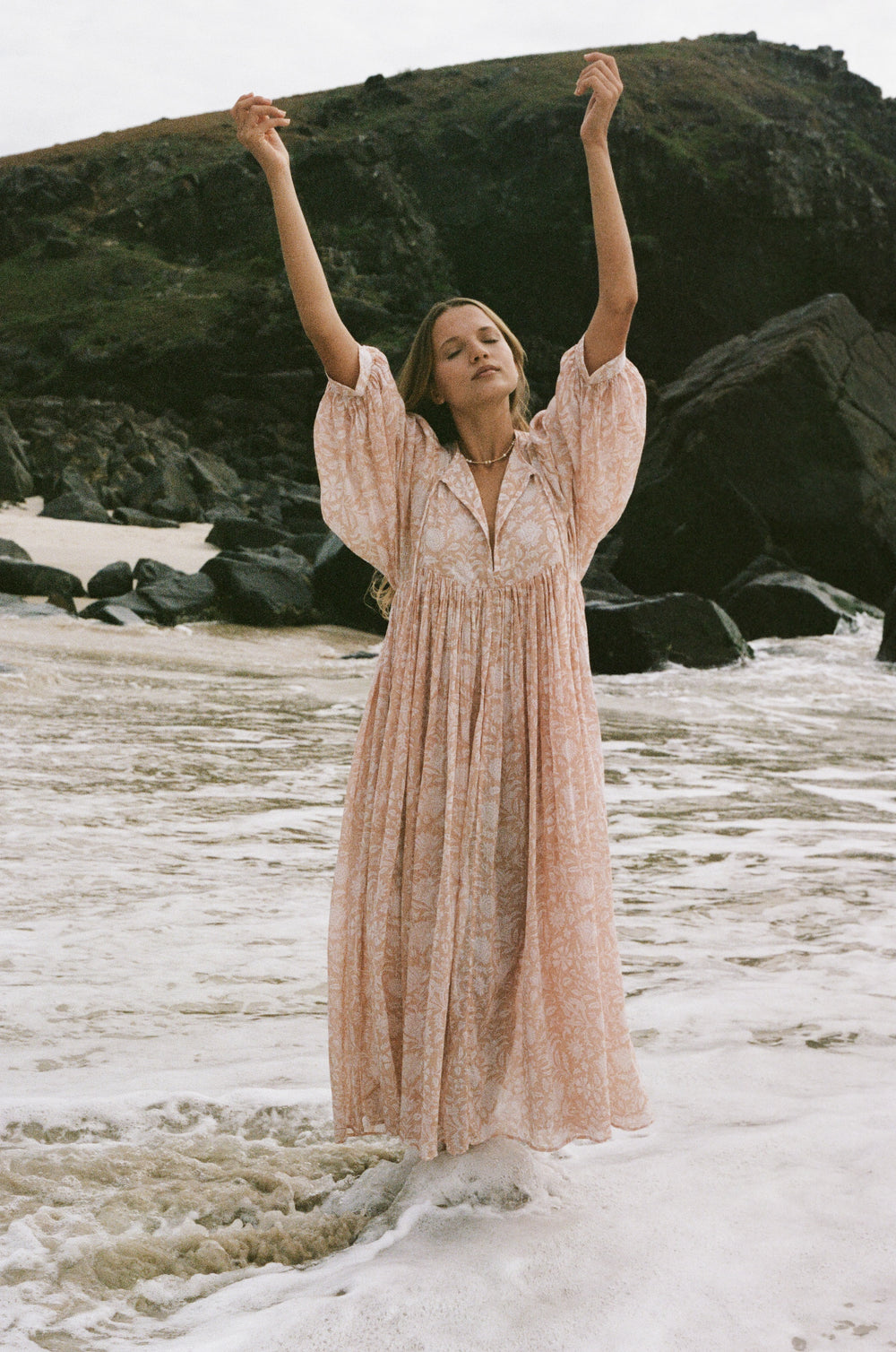Daughters of India Kyra Maxi Dress in Apricot Blush — arms raised in waves, flowing hand screen print cotton maxi