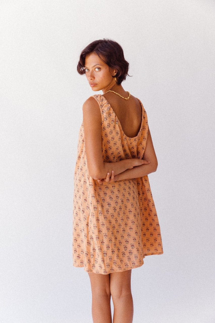 Sundress Mini Peach — upper body studio portrait, model smiling, tie-gather neckline detail visible, peach floral hand block print cotton, shoulder and neckline focus | Daughters of India