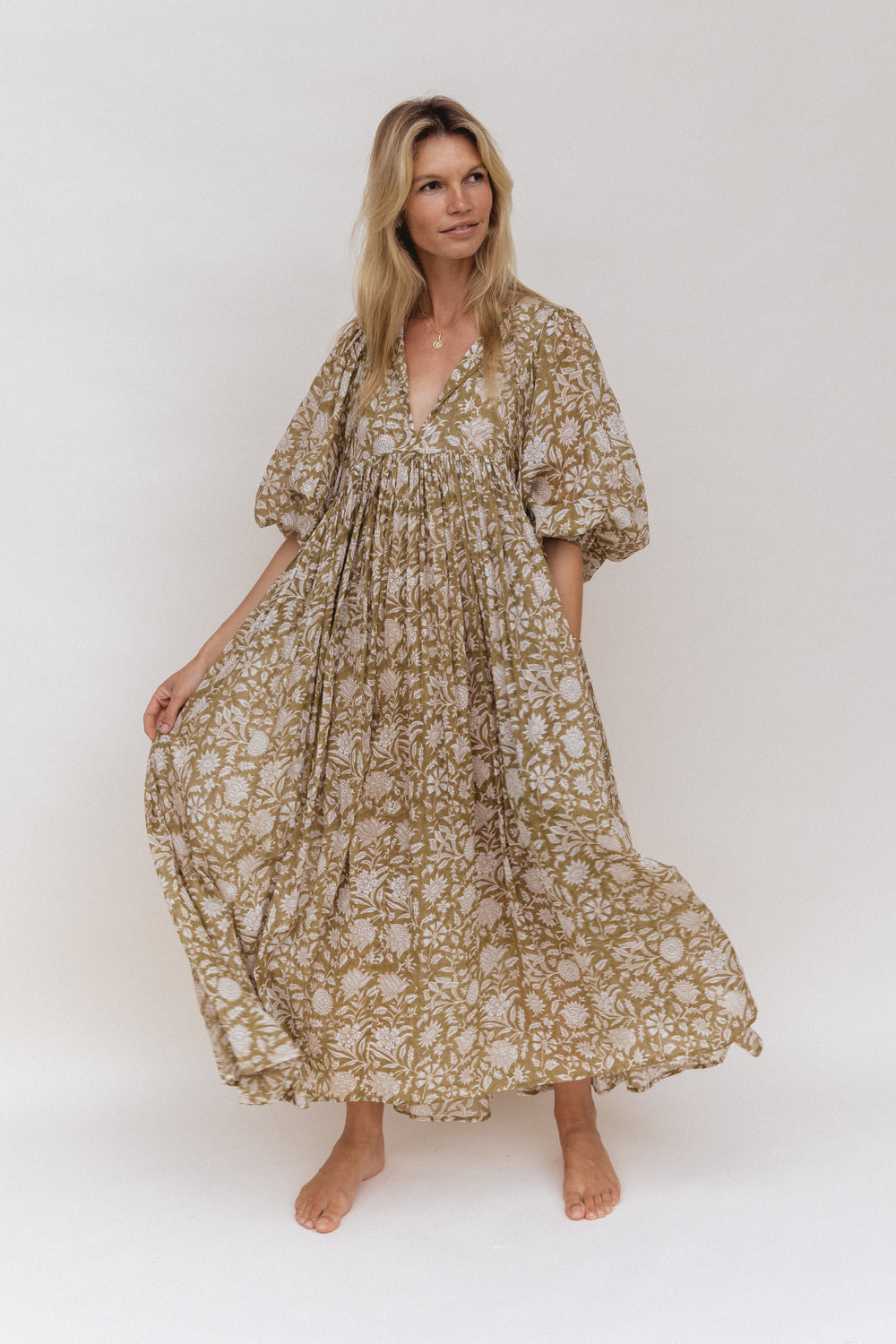 Daughters of India Kyra Maxi Dress in Olive — studio front view holding skirt, V-neckline, flowing hand screen print