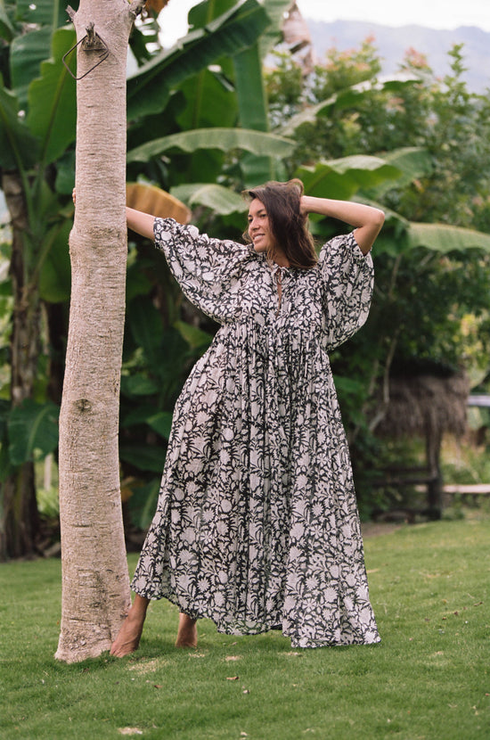Daughters of India Kyra Maxi Dress in Pepper — full length arms behind head, tropical garden with banana palms