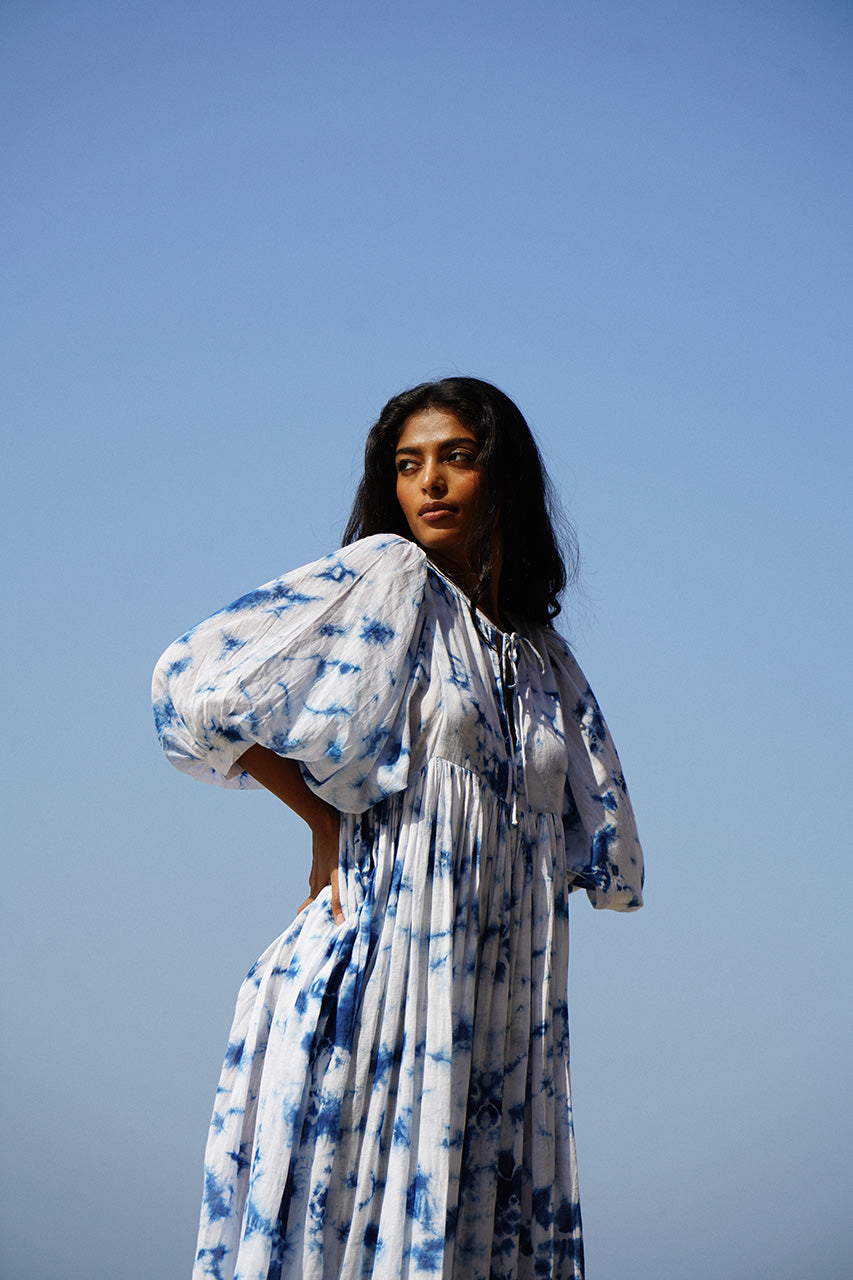 Kyra Midi Dress Deep Sea — side view on beach with wind-blown skirt, deep sea shibori tie-dye cotton midi dress showing flowing movement, coastal India | Daughters of India